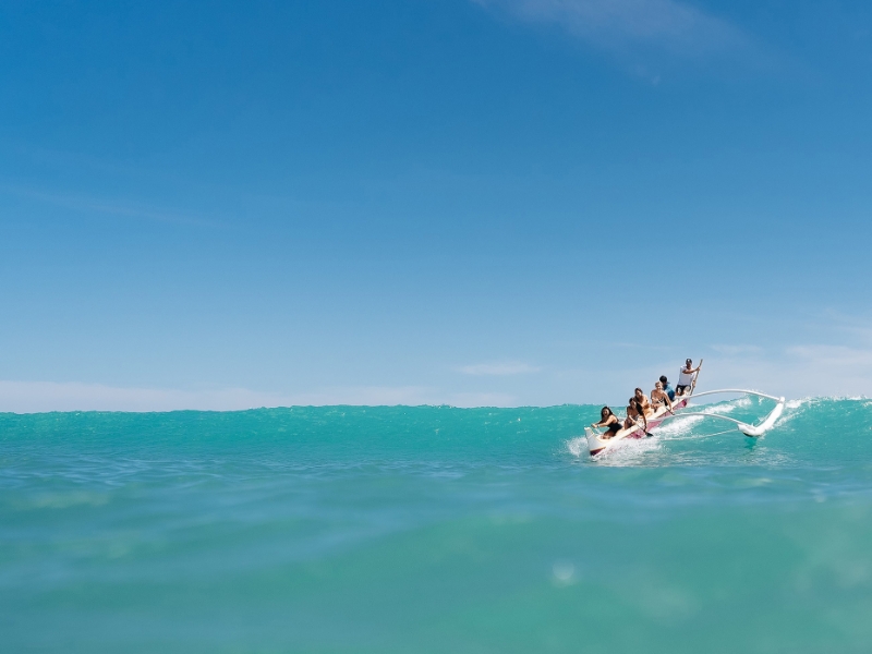 Catching waves while outrigger canoe surfing