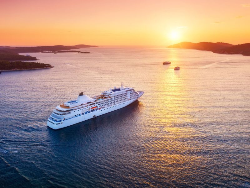 Aerial view cruise ship sailing across vast expanse water at sunset