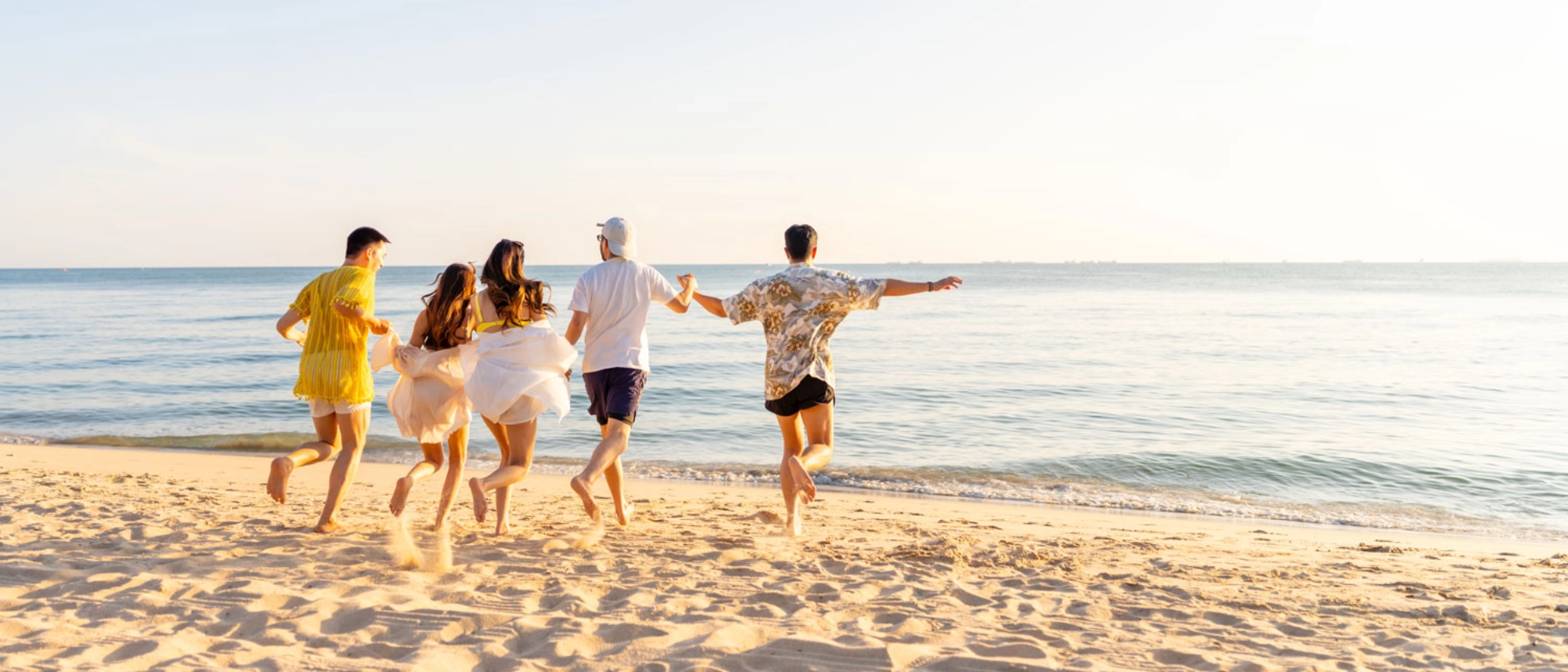 Group of friends running on the beach