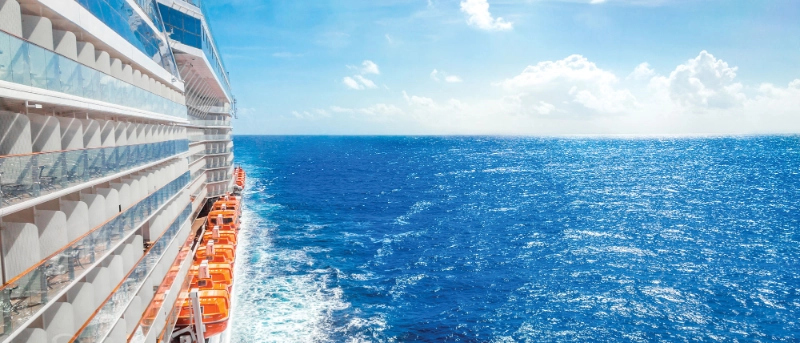 View from the side of a cruise ship sailing across the open ocean on a sunny day