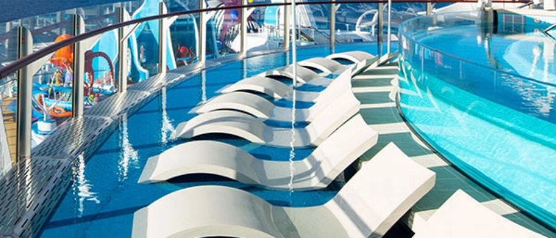 Cruise ship pool deck featuring in-water loungers and a relaxing outdoor pool